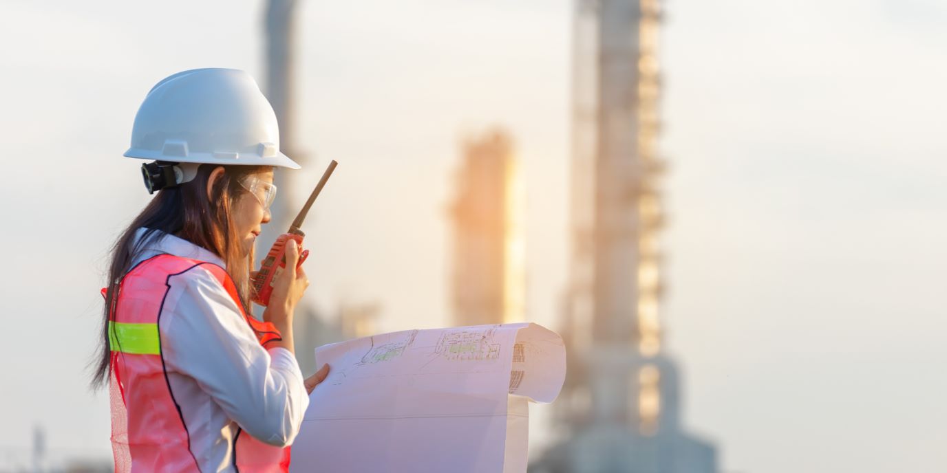 Female engineer holding a drawing and walky-talky