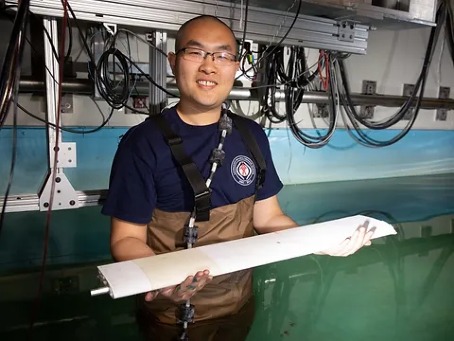 Dr Dixia Fan holding an item for experiments while standing in the water tank